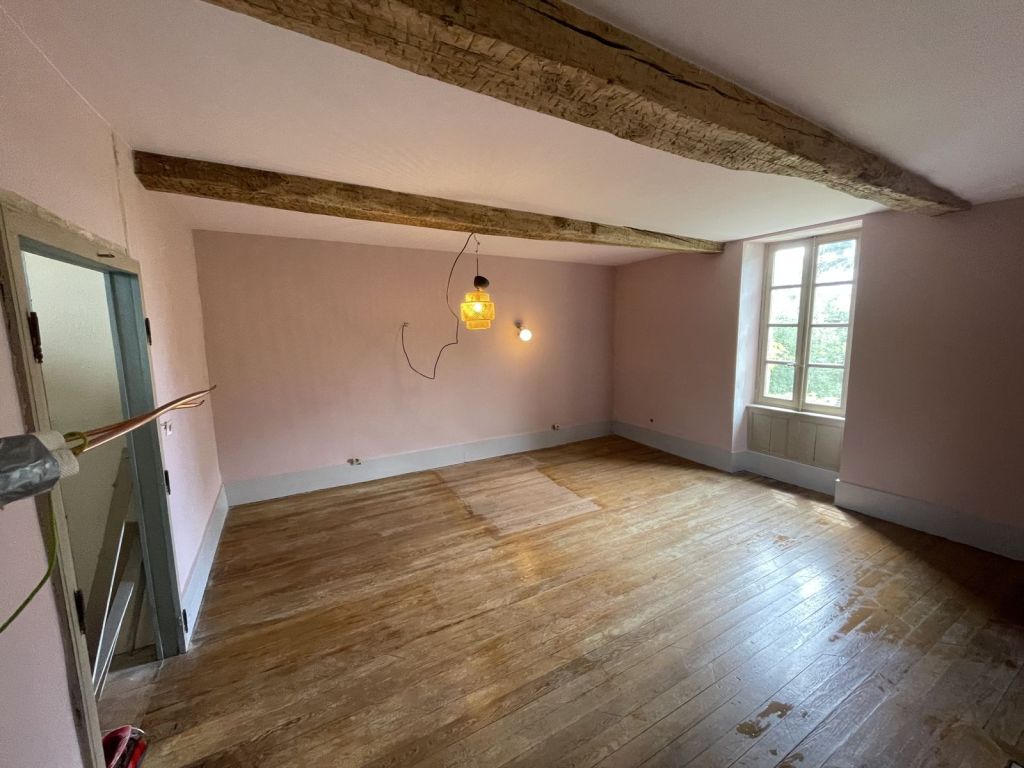 Pièce aux murs repeints en rose poudré et poutres apparentes
