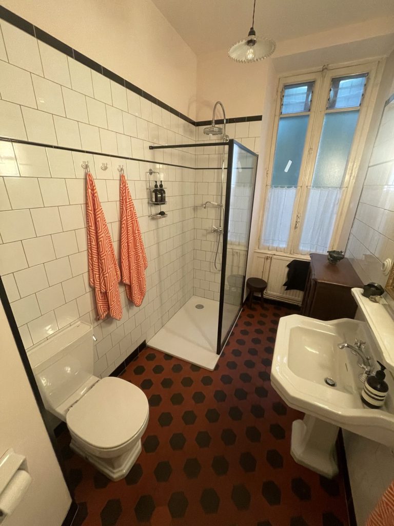 Salle de bains : douche à l'italienne, carrelage blanc et sol en carreaux hexagonaux