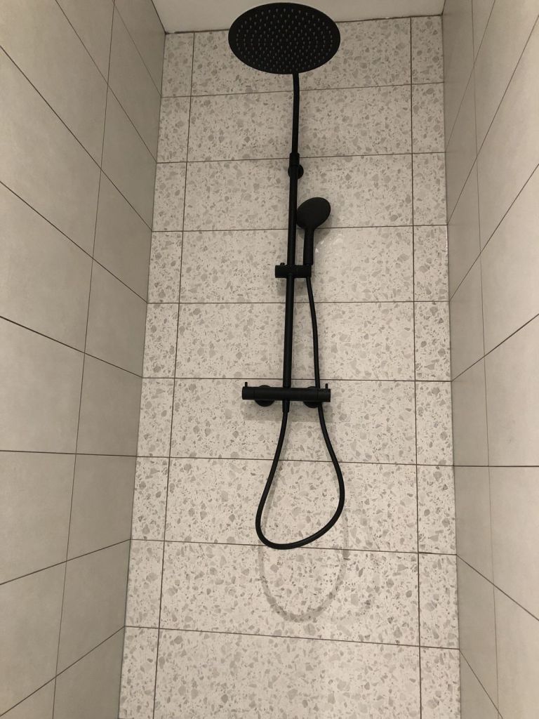 Douche avec colonne noire et panneaux effet terrazzo