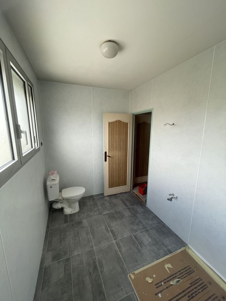 Salle de bains avec panneaux muraux clairs et carrelage gris